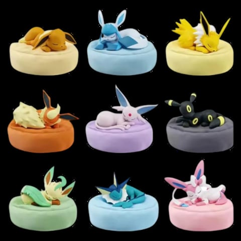 Grid of nine Pokémon figurines resting in colorful cushioned beds against a black background